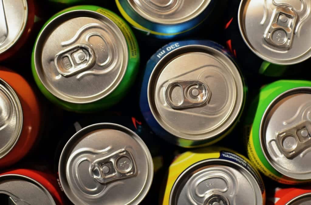 Colorful aluminum cans with pull-tab tops arranged on dark background.