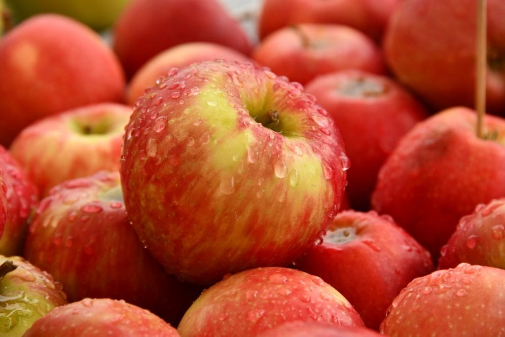 Fresh red apples with water droplets, a sugary food to avoid for dental health.