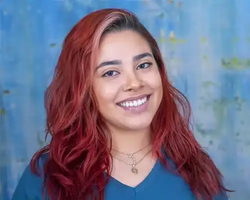 Female dental staff member with red wavy hair smiling at Lake Ridge dental practice.