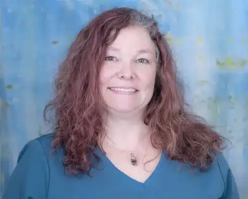 Staff member with long reddish-brown hair smiling at Lake Ridge dental practice.