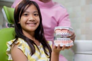 Young patient holding dental model showing orthodontic braces treatment at Lake Ridge dental practice.