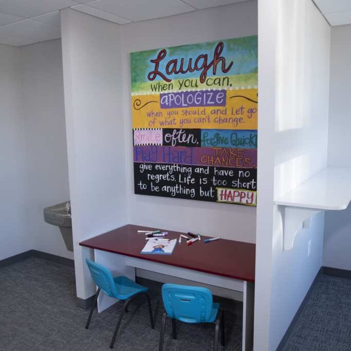 Modern orthodontic office workspace with motivational "Laugh" wall art and desk seating area.