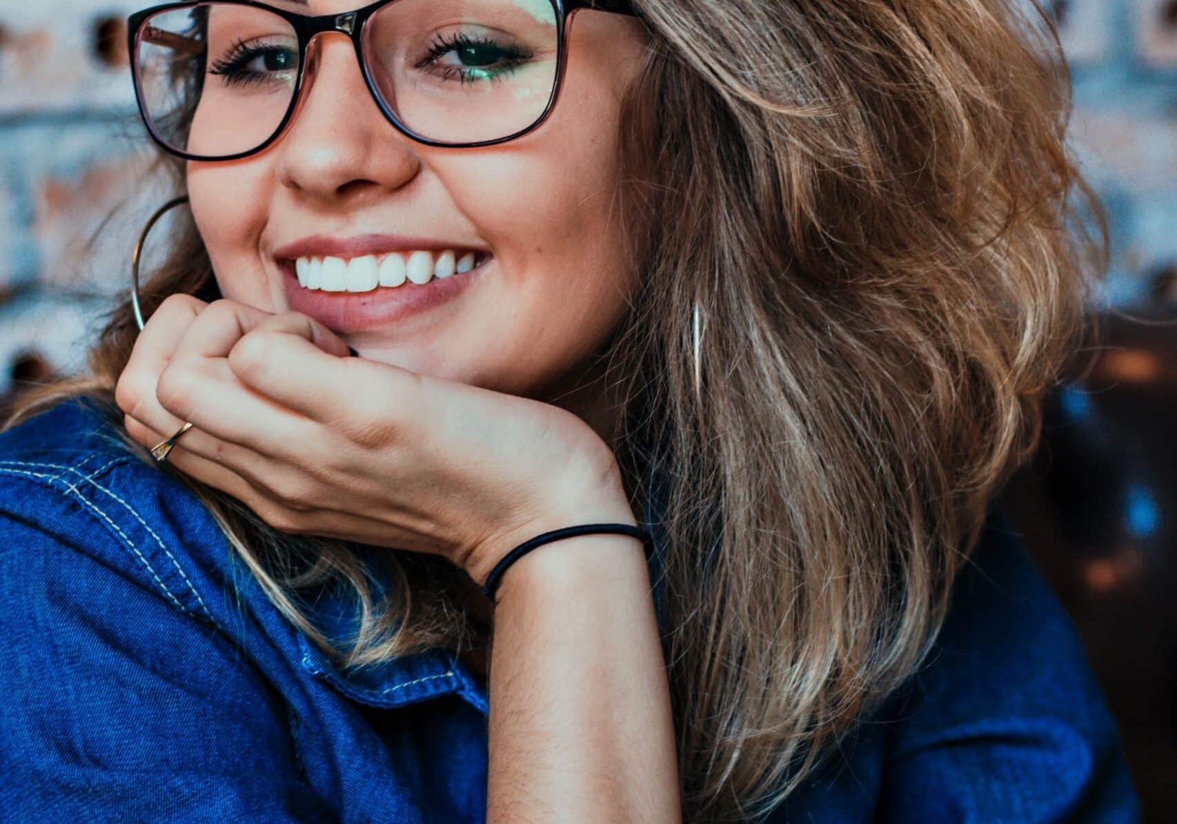 smiling woman in denim top and glasses